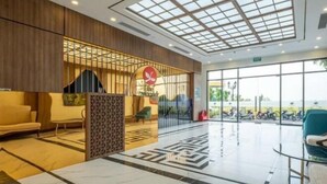 A modern lobby with a glass ceiling, a reception desk, seating area, and a view of the outside. - Sunshine Apartment - Vinhomes Ocean Park Ha Noi (Hanoi)