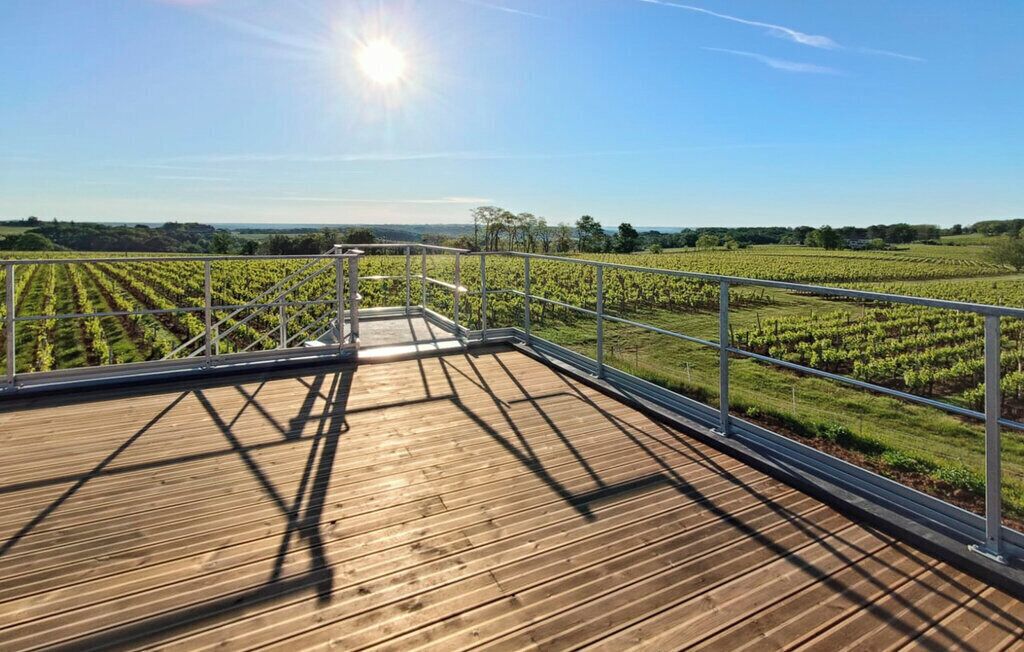 A wooden deck with metal railings overlooking a vineyard.