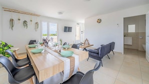 Un espace repas moderne avec une table en bois, des chaises noires et une vue sur l’extérieur.