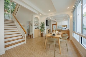 Una cocina amplia con comedor, piso de madera y una escalera que conduce a otro nivel.