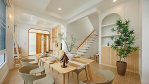 Un espace repas moderne avec une table en bois, des chaises et un escalier menant à une mezzanine.