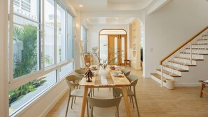 Un vaste espace dédié à la salle à manger, avec une longue table, des chaises et un escalier.