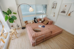 Una habitación acogedora con una cama, un escritorio, una silla, un ventanal y una planta.