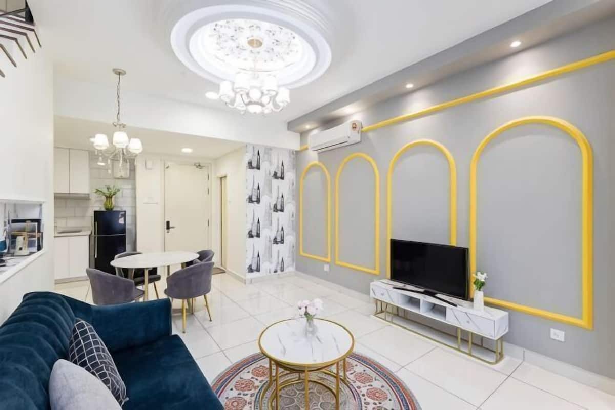A modern living room with a sofa, TV, and dining area.