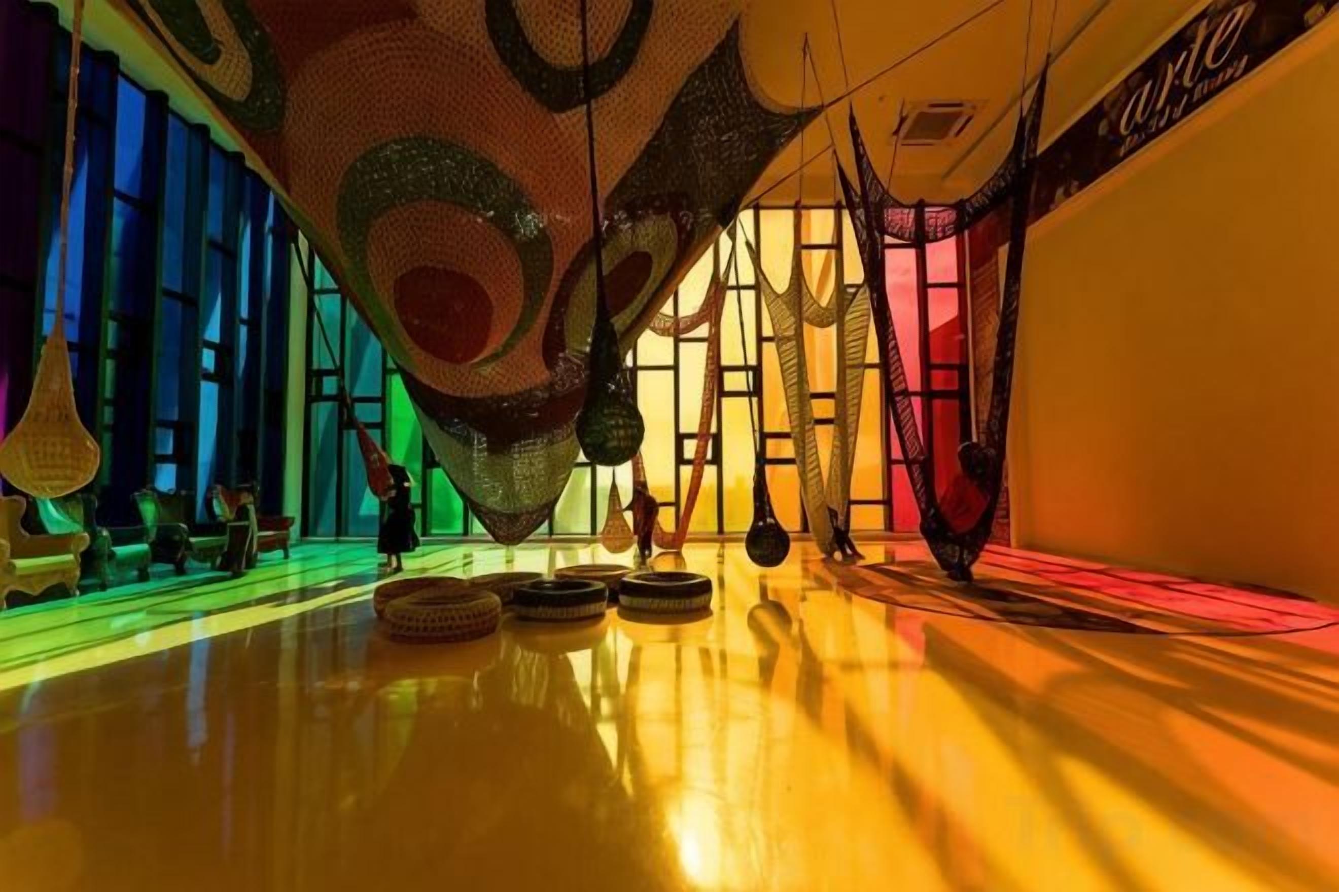 A modern interior with a reflective floor, abstract wall art, and a seating area with chairs.