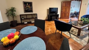 A living room with a round table, blue cushions, a TV, and a potted plant. - Excellent location in Antigua for 4 guests (Antigua Guatemala)