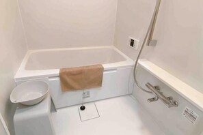 Una vasca da bagno bianca con un asciugamano marrone, un lavandino bianco e un pannello comandi doccia.