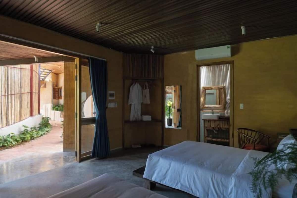 A bedroom with a bed, a bedside table, a mirror, and a window.