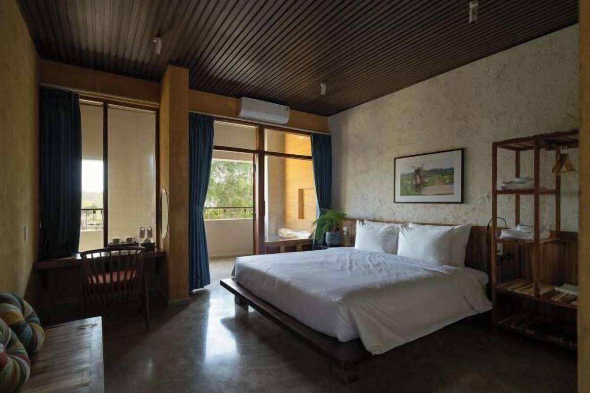 A bedroom with a large bed, a desk, and a chair.