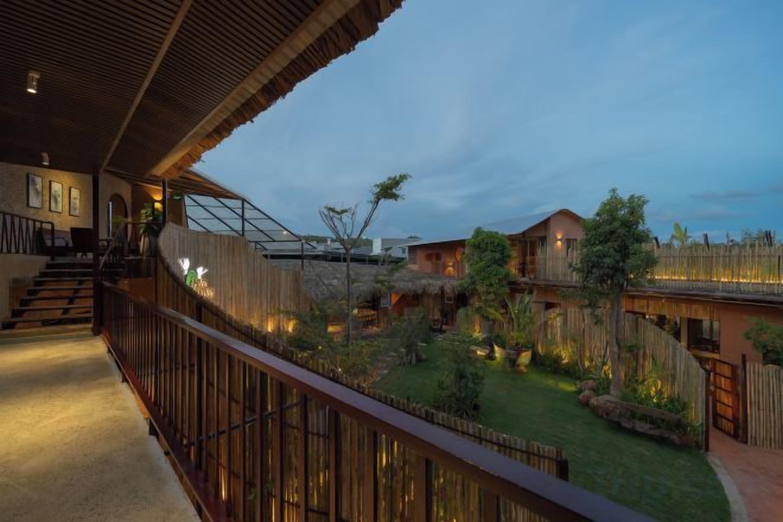 A hotel with a balcony, a staircase, and a well-maintained garden.