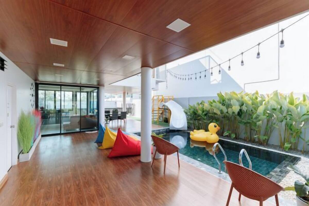 A modern indoor pool area with a wooden ceiling, colorful seating, and a small inflatable duck.
