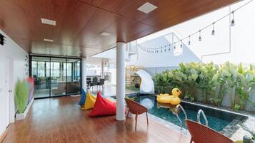 Un área de piscina interior moderna con techo de madera, asientos coloridos y un patito inflable.