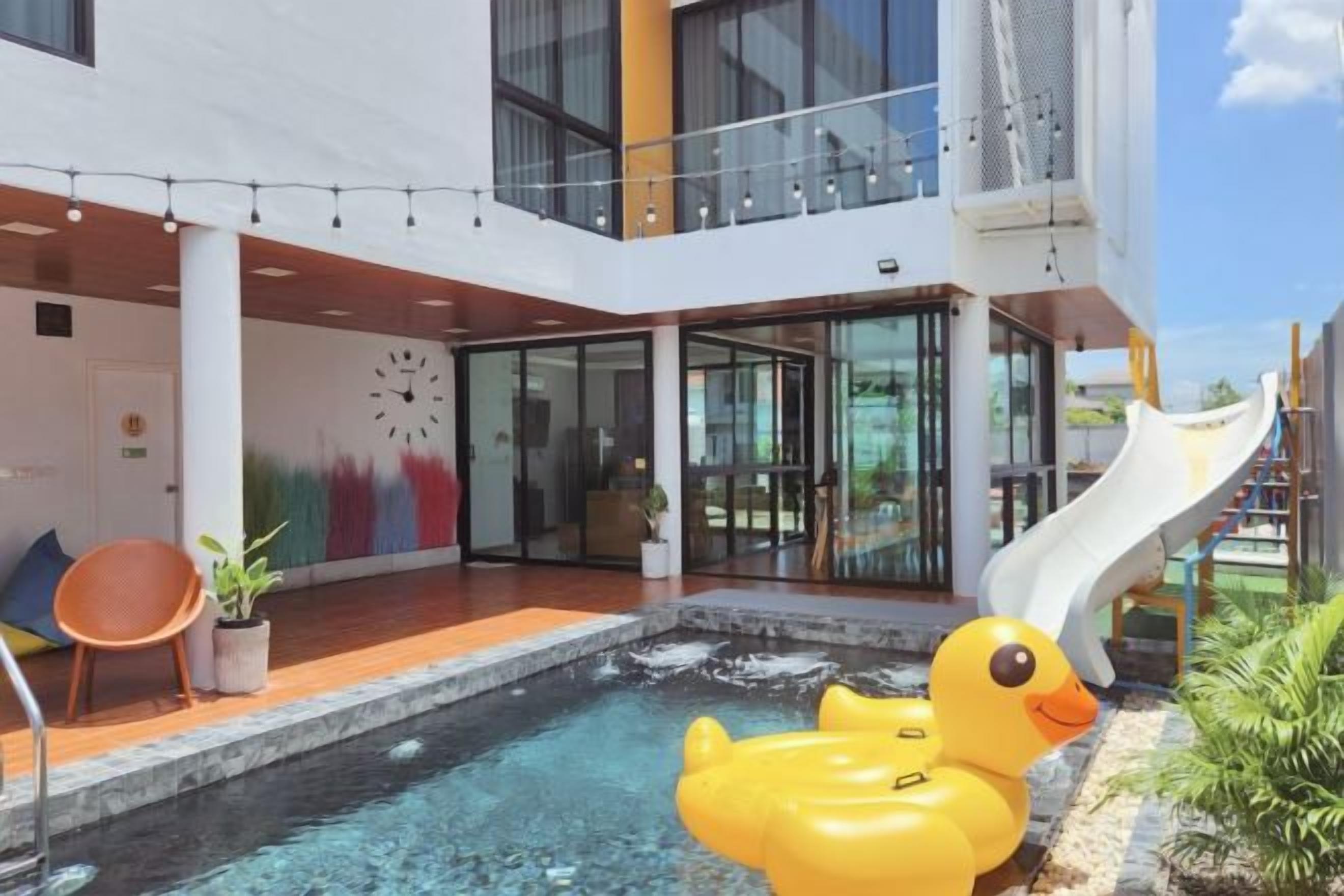 A modern building with a pool, a duck float, and a slide.