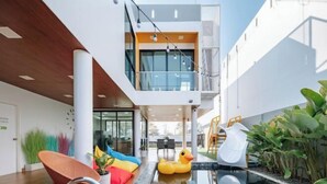 A modern indoor pool area with a glass balustrade, a slide, and a small inflatable duck. - Riverfront Pool Villa Rangsit Klong 4 (Thanyaburi)