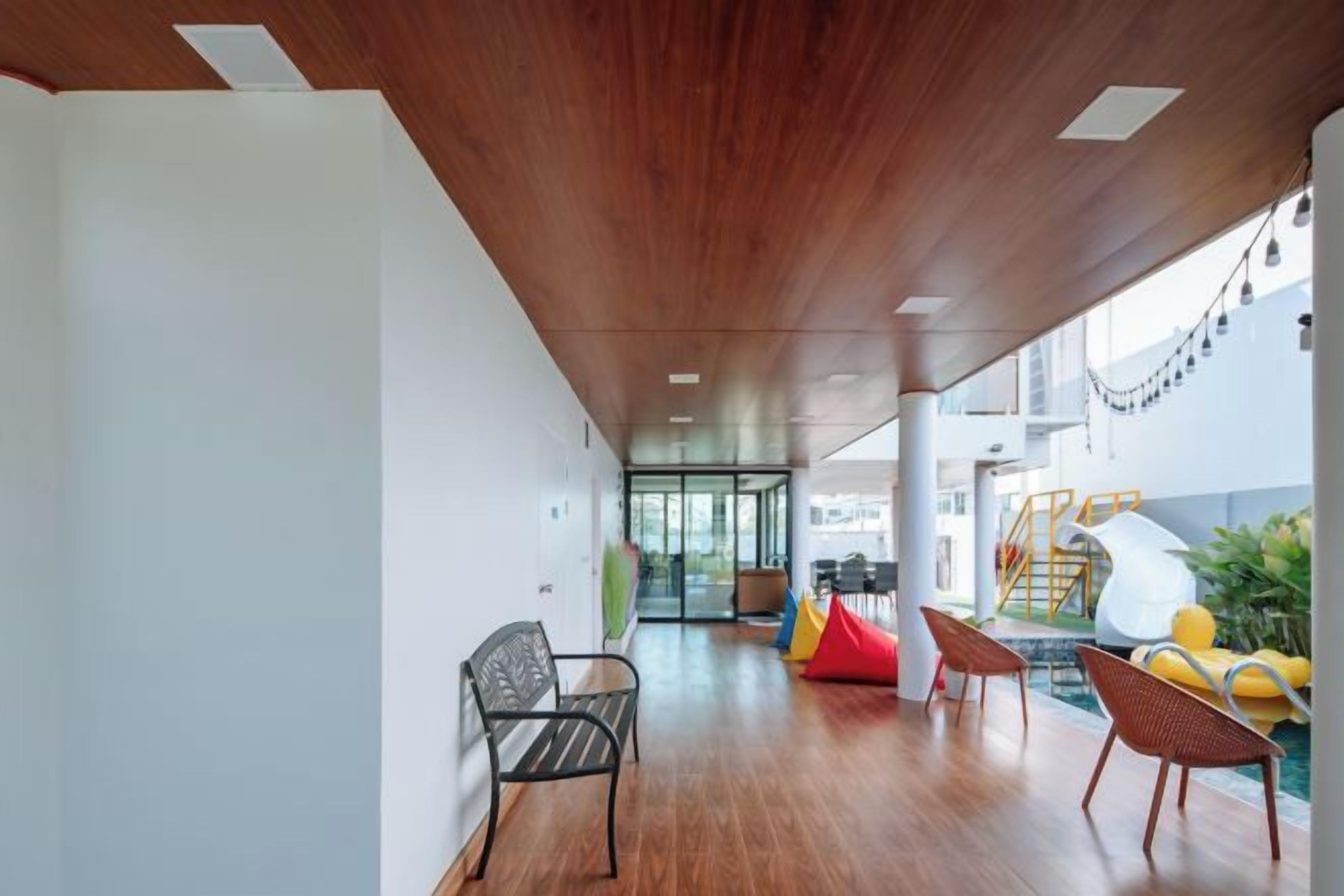 Un espacio interior amplio con piso de madera, un techo alto y vista a un área de juegos al aire libre.