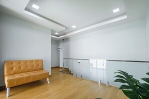 Ein Zimmer mit Holzboden, einer Couch, einer Treppe und einer Pflanze.