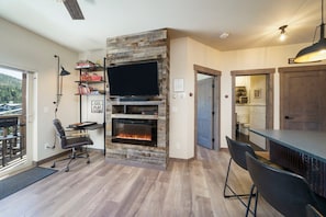 A modern living room with a fireplace, a flat-screen TV, and a dining area.
