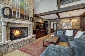 A spacious living room with a stone fireplace, a large sectional sofa, and a television.