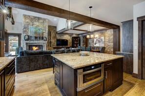 Une cuisine moderne avec une cheminée en pierre, un four encastré et un grand îlot central.