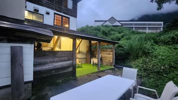 A traditional Japanese house with a wooden exterior, a covered outdoor seating area, and a small garden.