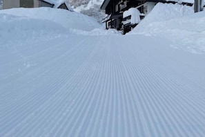 A snow-covered path leading to a building with a sloped roof.