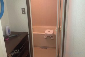 A bathroom with a toilet, a small shelf with a bottle and a cup, and a vent on the wall. - Lodge noel (Minamiuonuma)