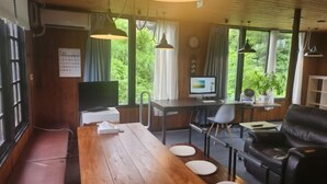 A modern room with a wooden table, black leather sofa, and a desk with a computer. - Lodge noel (Minamiuonuma)