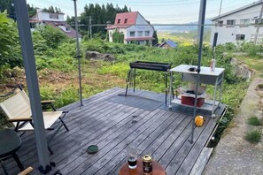 A wooden deck with a table and chairs, a keyboard, and a speaker. - Lodge noel (Minamiuonuma)