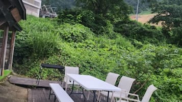 An outdoor patio with a table and chairs, surrounded by lush greenery.