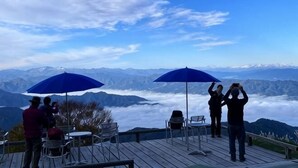A deck with chairs and tables, overlooking a mountainous landscape with a clear sky. - Lodge noel (Minamiuonuma)