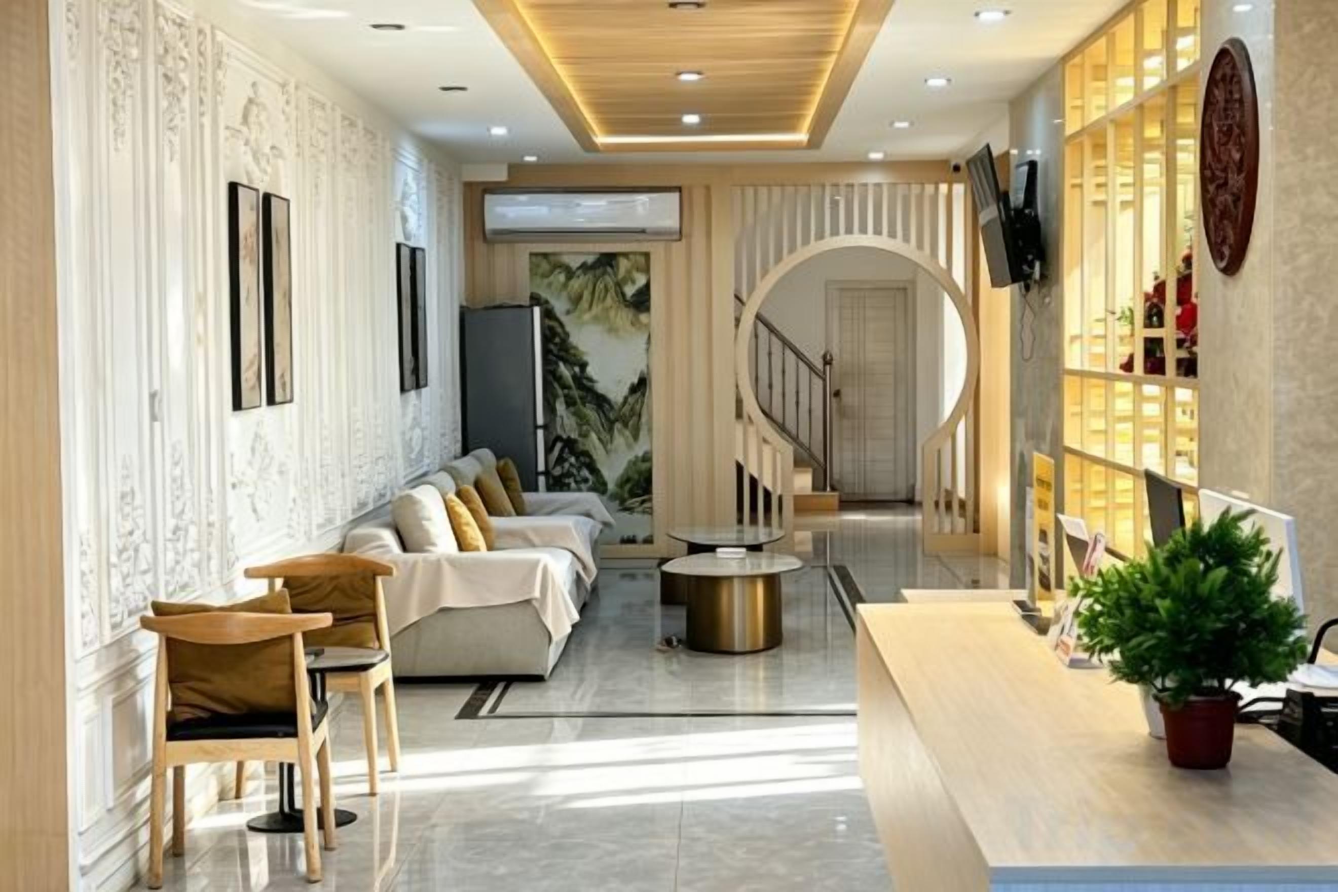 Una sala de estar moderna con un sofá, sillas, una mesa de centro y un televisor. Hay una escalera que lleva a un piso superior.