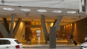 Ein modernes Gebäude mit geometrischer Architektur, ein Empfangsbereich mit Glasfassade und ein Parkplatz mit Autos.