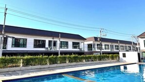 A modern hotel with a swimming pool, white exterior, and multiple windows. - Pattaya Tay Emperor Holiday townhouse (Pattaya)