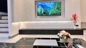 A modern reception area with a large flat-screen TV mounted on the wall, a reception desk with a laptop, and a vase with flowers. - Pattaya Tay Emperor Holiday townhouse (Pattaya)