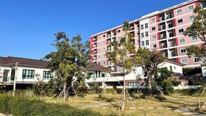 A multi-story residential building with balconies, surrounded by greenery and a clear sky. - Pattaya Tay Emperor Holiday townhouse (Pattaya)