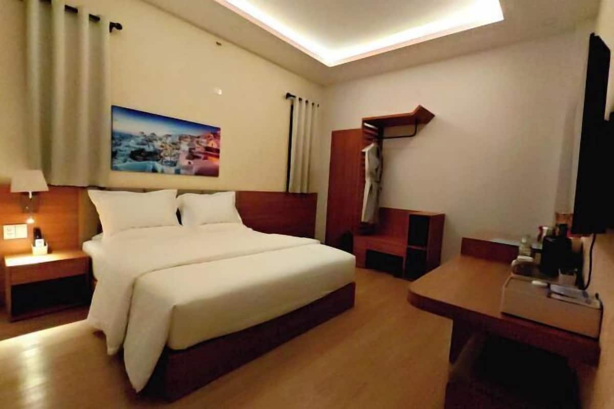 Une chambre d’hôtel avec un grand lit, un bureau, une chaise, une télévision et un tableau au mur.