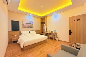 Una habitación de hotel moderna con cama, escritorio, silla y armario.