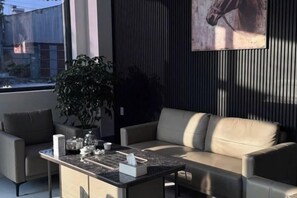 A modern living room with a sofa, a coffee table, and a potted plant. - ELLMAN Boutique Hotel (Thuan An)