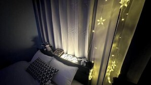 A bedroom with a bed, curtains, and string lights. - Nakano5chome-102 (Tokyo)