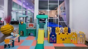 Een kinderspeelplaats met een glijbaan, speeltoestellen en veiligheidshekken.