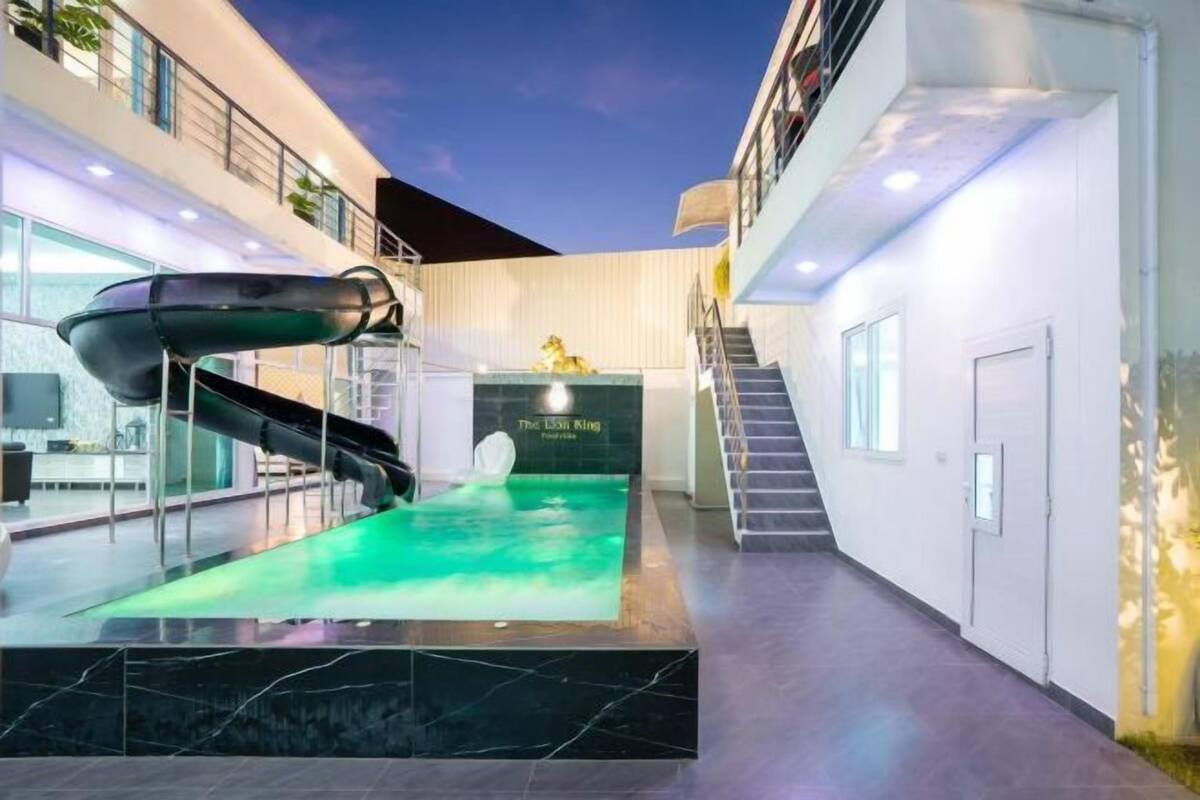 A modern indoor pool area with a slide, stairs, and a sign reading "The Lion King."