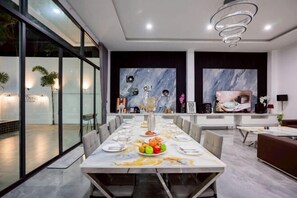 A modern dining area with a long table set for a meal, surrounded by chairs. - THE I-CON Luxury PoolVilla Pattaya "10 bed" Ocean Yacht Club 4 km (Pattaya)