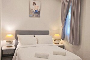 A neatly made bed with white linens and two pillows, two bedside lamps, a framed picture on the wall, and a window with curtains. - 90/9 Pool Villa Chiang Mai (Chiang Mai)