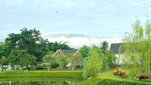 A serene lakeside setting with a house, trees, and a pond. - 90/9 Pool Villa Chiang Mai (Chiang Mai)