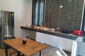 A compact kitchen with a stainless steel refrigerator, a wooden table with a potted plant, and a countertop with various kitchen items. - 90/9 Pool Villa Chiang Mai (Chiang Mai)