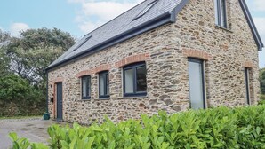 A stone building with a sloped roof and multiple windows. - Ewe Barn (St Austell)