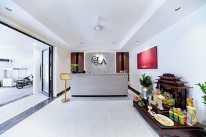 Een hotel receptie met een receptiebalie, een aan de muur bevestigde televisie en een decoratief altaar met aanbiedingen.