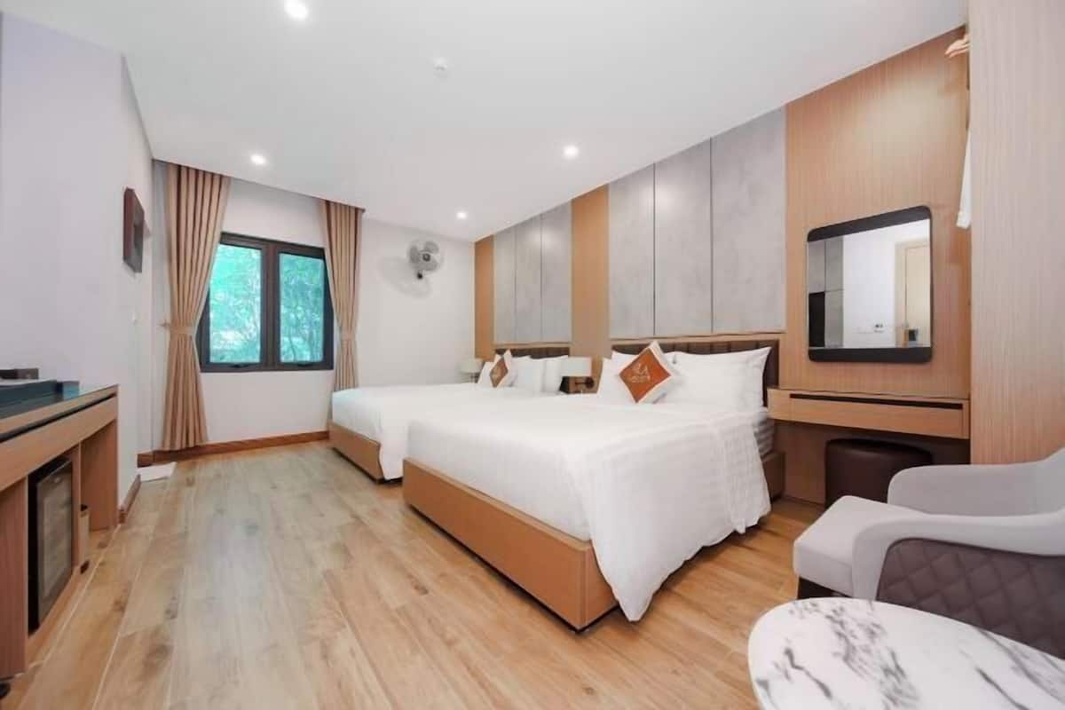 Une chambre d’hôtel avec deux lits, un bureau, une chaise, un miroir et une fenêtre.