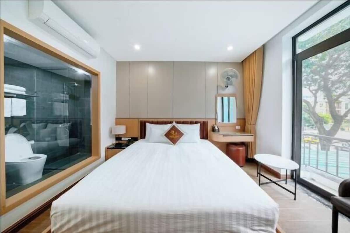 Une chambre d’hôtel avec un grand lit, un bureau, une chaise et une fen être donnant sur un beau paysage.