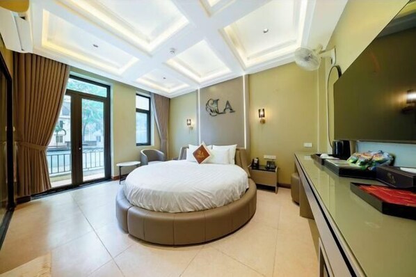 Une chambre d’hôtel avec un lit rond, une télévision, un bureau et un balcon.